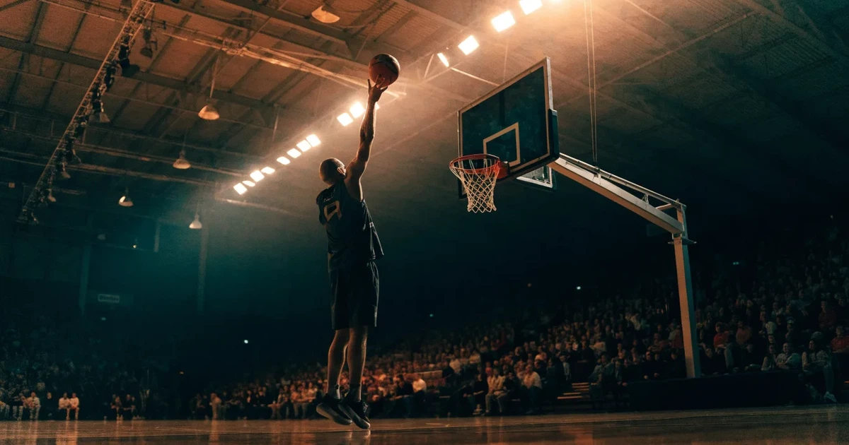 Eine leere Basketballhalle mit glänzendem Parkett und einem Korb im Hintergrund, Licht von Deckenstrahlern spiegelt sich im Boden.